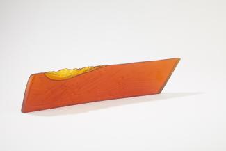 Long, rectangular glass sculpture. Colour is burnt orange.