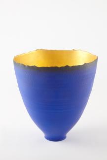 Glass vase with narrow bottom and wide opening at top. Royal blue exterior and gold interior.