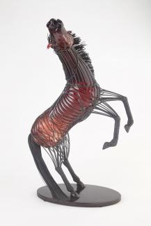 Glass sculpture encapsulated in wire. Is in the shape of a rearing stallion, black and red in colour. 