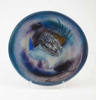 Round glass plate with abstract design of blues, purples, black and gold.