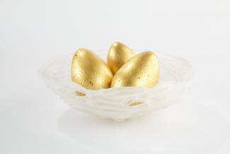 Glass bowl holding three golden eggs