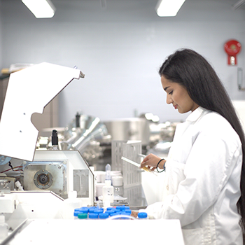 Photo of woman wearing a white lab coat working in a lab environment